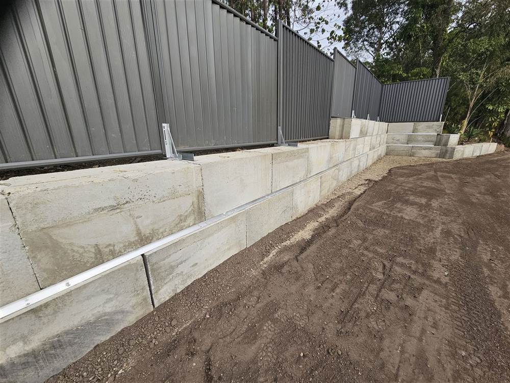 Long concrete block retaining wall with a stepped return